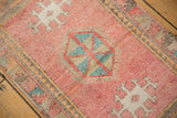 Distressed blush Oushak rug with geometric medallion and faded blue, tangerine colors.