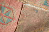 Distressed Oushak rug with blush geometric pile, hand-knotted foundation, and visible fringe.