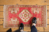 Feet on distressed Vintage Oushak rug, highlighting blush field and ivory medallion.