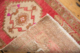 Distressed Oushak rug's blush, raspberry, and ivory low pile, revealing its foundation.