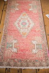 Vintage distressed Oushak runner, showing blush pink pile, geometric border, and fringe.