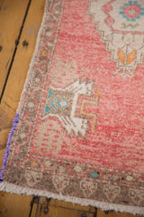 Textured distressed Oushak rug corner, blush field, purple selvage, turquoise detail.