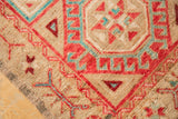Distressed Oushak rug detail, highlighting cherry red and aqua blue geometric hook and latch motifs.