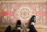 Softened blush, ivory, and beige geometric medallion on a distressed Oushak rug mat.