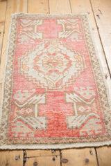 Fringe and worn blush, ivory, coffee brown pile on distressed Oushak rug's edge.