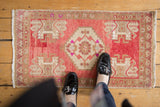 Hand-knotted vintage distressed Oushak mat displaying raspberry medallion and simplified plant motifs.
