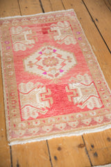 Vintage distressed Oushak rug corner with pink, ivory geometric motifs and visible fringe.