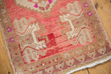 Distressed Oushak rug corner with low pile, raspberry, beige, and plum geometric border detail.