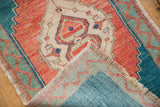 Folded corner of the distressed Oushak rug shows fringed edge and hand knotted turquoise back.