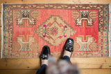 Distressed vintage Oushak runner with raspberry red, beige, and blue serrated medallion design.