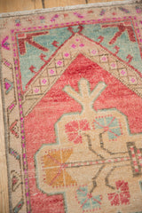 Distressed corner of vintage Oushak rug with blush, mint green, ivory, and dusty gold tones.
