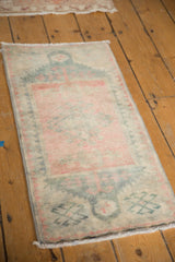 Low pile, secured edge of vintage distressed Oushak rug with dusty rose and teal patterns.