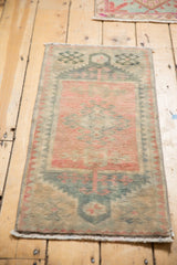 Distressed low pile of the vintage Oushak rug with geometric medallion in dusty rose and teal.