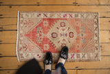Distressed vintage Oushak rug corner with abrash, floral motifs, and fringe.