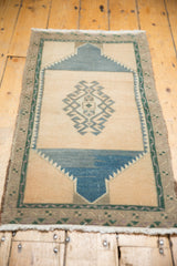 Distressed Oushak rug corner, showing sand field with serrated green geometric border.