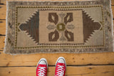 Distressed Oushak rug corner with visible even wear, serrated contour, sand, and chocolate tones.