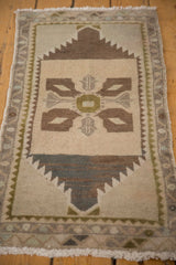 Distressed Oushak rug corner with fringe, meandering border, and serrated sand, chocolate motifs.