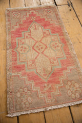 Distressed Oushak rug corner showing blush, beige, and soft blue geometric pattern with fringe.