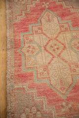 Secured side of the distressed Oushak rug mat, with blush, beige, and powder blue motifs.