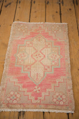 Distressed vintage Oushak rug corner, highlighting blush, beige geometric floral motifs and fringe.