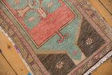 Distressed Oushak rug corner, showcasing even wear, blush, seafoam, charcoal tones, and fringe.