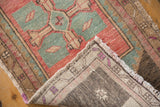Distressed vintage Oushak rug corner, showing hand-knotted reverse and ivory fringe.