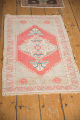 Distressed vintage Oushak rug, showing soft brick red border and ivory field with blue accents.
