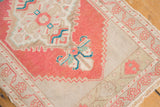 Corner of vintage distressed Oushak rug showcasing brick red, ivory, and aqua scrolling.