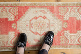 Softened knot heads on a distressed Turkish Oushak rug's blush pink, ivory, and coffee medallion.