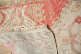 Distressed Oushak rug: low pile with even wear, hand-knotted back, and pink fringe.