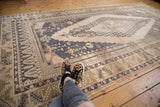 Distressed Oushak carpet with elongated medallion and wide borders in antique ivory and dusty navy.