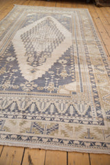 Distressed Oushak rug fringe and serrated leaf border in dusty navy and ivory.