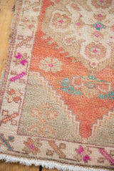 Hand-knotted Oushak rug fringe and distressed side selvage, with beige, brick red, and fuchsia motifs.