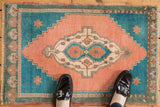 Vintage distressed Oushak rug mat; apricot peach oblong medallion, deep turquoise stepped spandrels.