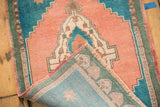 Hand-knotted vintage Oushak rug corner revealing woven back, fringe, and distressed apricot pile.