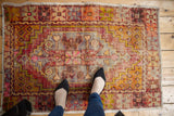 Decorative distressed vintage Oushak rug with faded aubergine, saffron, and pink medallion.