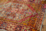 Distressed Oushak rug, worn texture, geometric patterns, and muted gold, pink, aubergine colors.