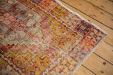 Distressed Oushak rug corner, showcasing textured pile wear in saffron, pink, and aubergine.