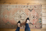 Distressed Oushak runner's stepped medallion, pale blush, ivory field, charcoal patterns, and blue accent.