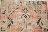 Distressed Oushak runner corner, faded blush field, black geometric motifs, visible blue show-through.