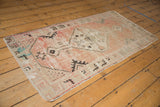 Distressed vintage Oushak rug corner showing pale blush, ivory, and charcoal motifs.
