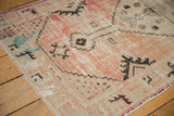 Worn blush rose pile on a distressed Oushak rug, featuring ivory, black motifs, and blue show-through.