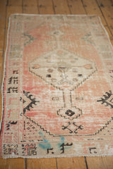 Distressed Oushak runner corner, blush field, ivory border, black patterns, fringe, blue marks.