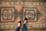 Distressed Oushak rug: rectilinear medallions, starburst, terra cotta, and chocolate brown colors.