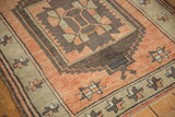 Low pile Oushak rug corner, showing distressed terra cotta, brown, and beige geometric motifs.