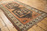 Distressed vintage Oushak rug corner; low pile, starburst border of terra cotta, beige.