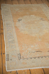 Distressed Oushak rug corner, worn pile showing pale terra cotta and ribbon motifs.