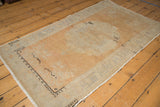 Distressed Oushak rug corner showing mostly even wear, pale terra cotta, silver border.