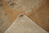Distressed Oushak rug's worn pile texture and a light beige tightly woven foundation.