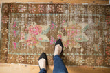 Distressed Oushak rug with textural pile, featuring vibrant floral motifs in blush, bronze, sea foam.